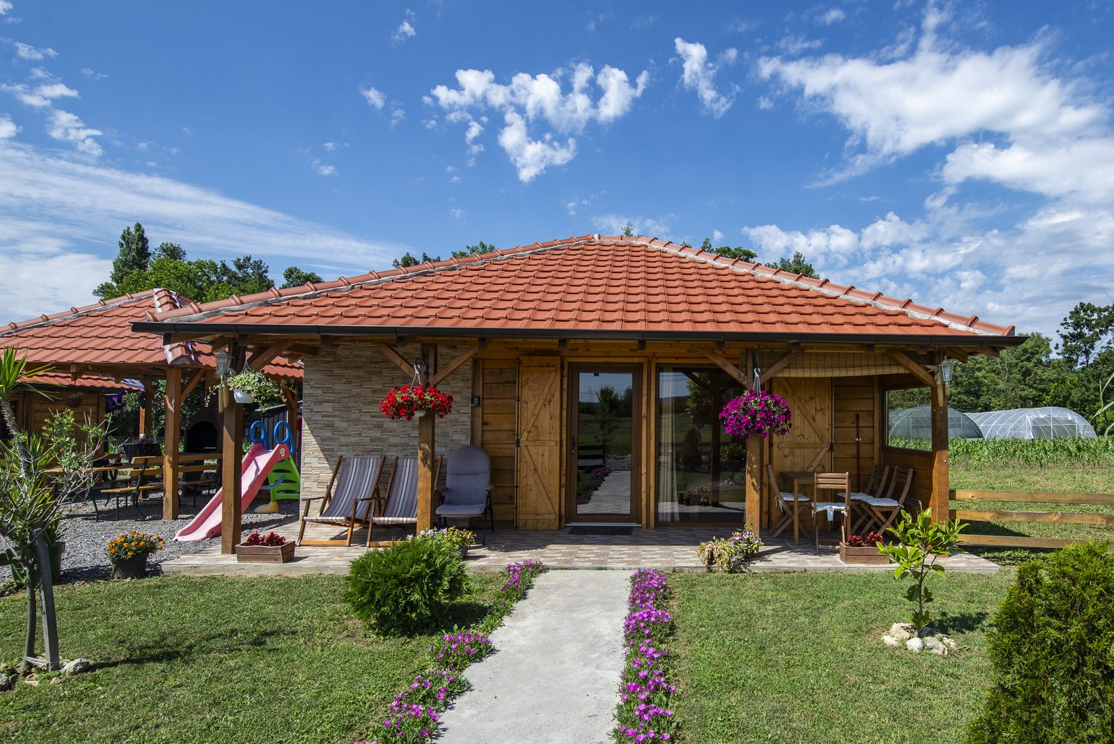 Apartman Dača 3 — drvena kućica sa terasom, u zelenilu i cveću